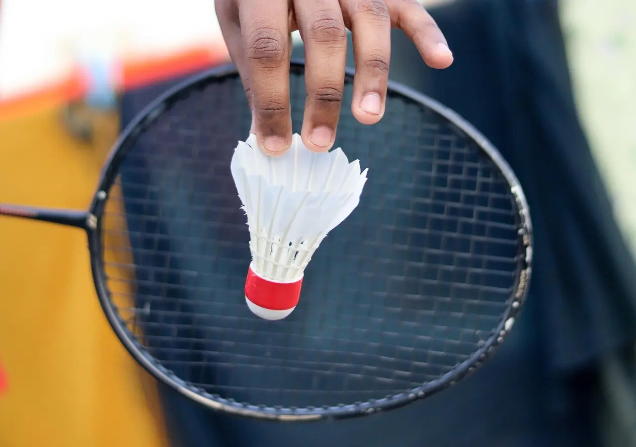 Fjerbold og badmintonketcher i en hånd
